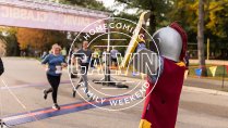 Calvin mascot Joust cheering runners across the finish line.