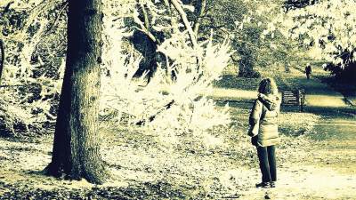 A woman stands in front of a tree in the winter.