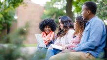 Three Calvin University students sitting on Commons Lawn studying in Grand Rapids, Michigan