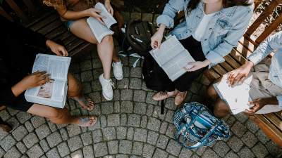 A photo from above of students sitting on benches, with a patterned stone patio beneath them