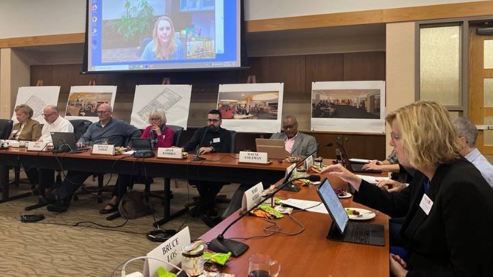 Members of the board of trustees sitting at tables with name cards in front of them.