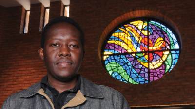 Stephen Okeyo by a stained glass window in the college chapel.