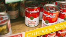 Soup cans stacked on a shelf of a food pantry