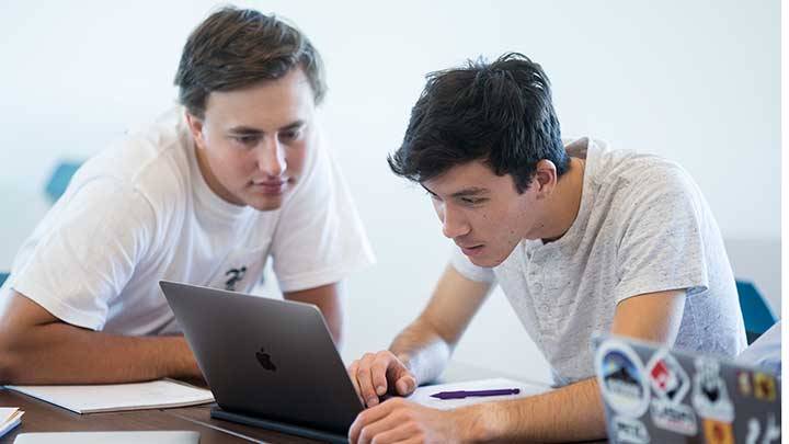 Two people sitting across a table, zoomed into to their hands and other things on the table