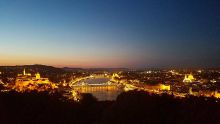 A cityscape at night of downtown Budapest, Hungary alongside the Danube River.