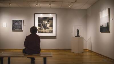 Donna Spaan '55 seated in the gallery, viewing artwork.