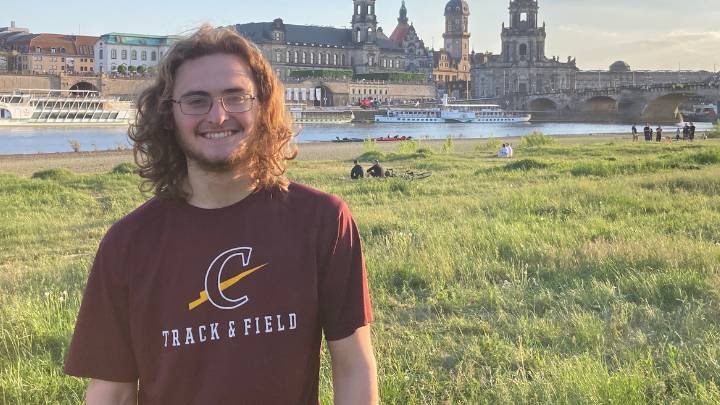 Jonathan Holdridge standing in Europe with a river and buildings behind him.