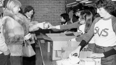 KIDS volunteers hand out food to people.