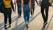 A back view of a group of high school students walking together on a path.