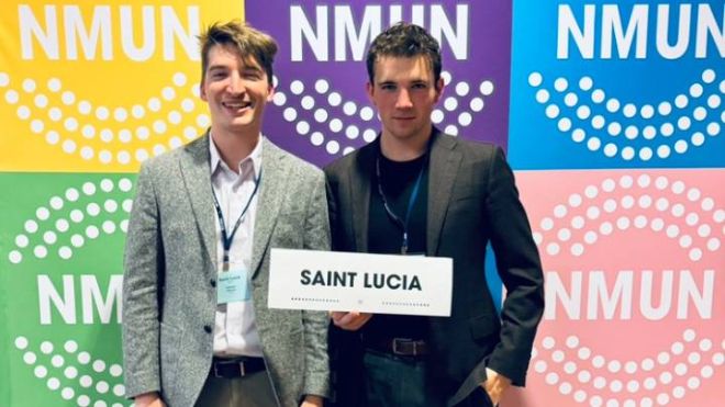 Two Calvin students stand, one holding a sign that says Saint Lucia on it.