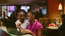 Two women with an open laptop sit at the counter at Johnny's Cafe.