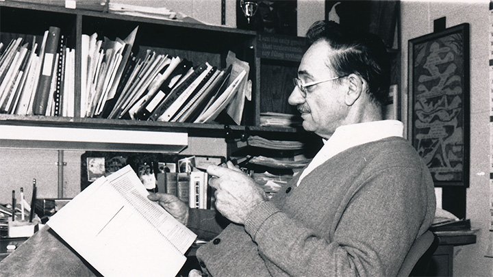 Donald Oppewal, 1926-2018, enjoys his pipe while reading in his office.