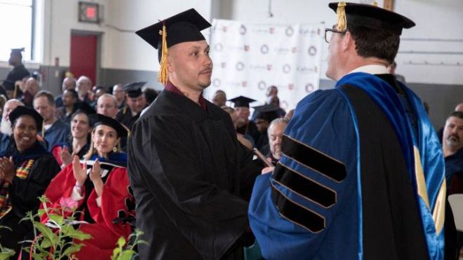 2023 grad Jeff Mata receives his diploma from Provost Noah Toly during the 2023 Commencement ceremony at Handlon Correctional Facility.