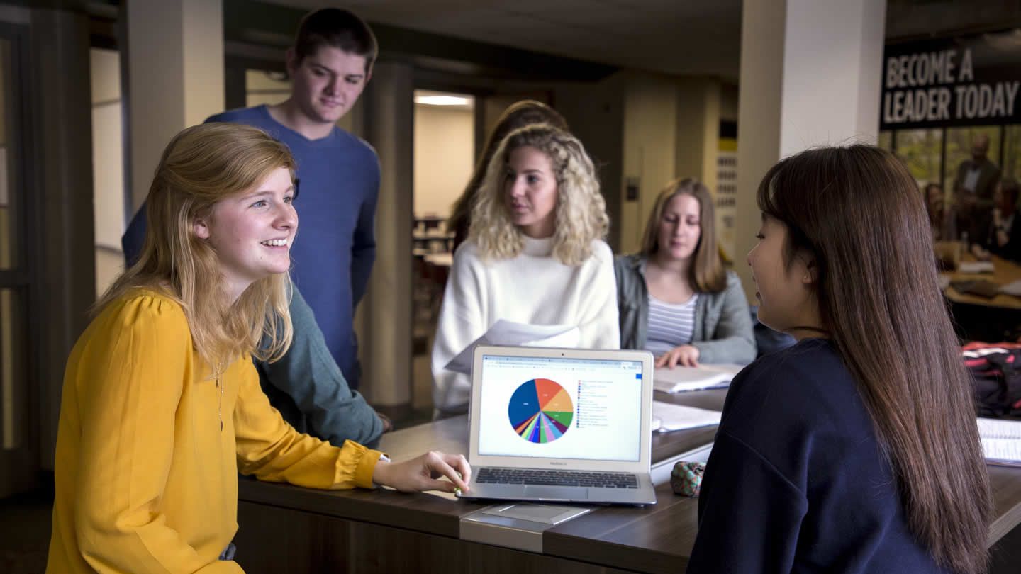 Business students meeting at a table, conversing 