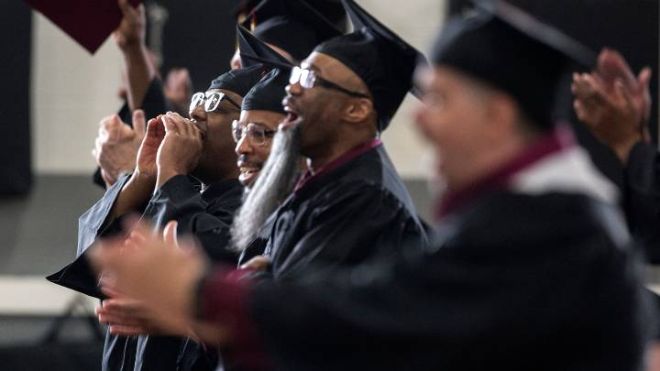 Graduates standing and applauding.