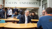 A classroom setting with inmates talking to leaders in suits and ties.