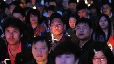 A group of persecuted Christians gather together and hold candles.