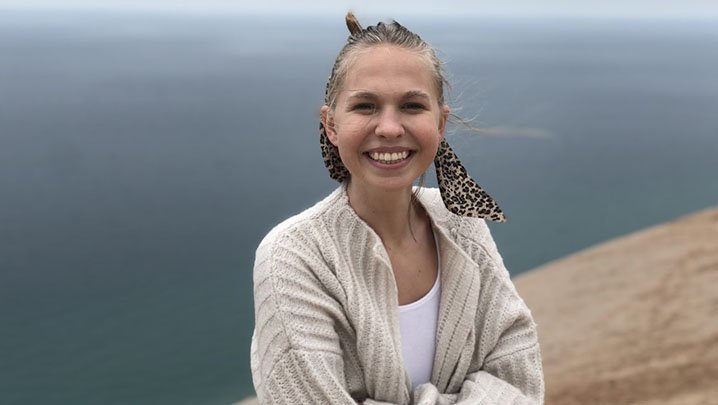 A girl smiling with a blue sky behind her.