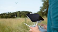 A student flying a drone over an open field.