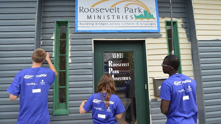 Three students painting the outside of a building in Grand Rapids, Michigan.