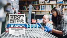 A professor and a student doing research, peering at a water filter.