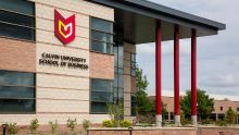 A brick building with large windows, red pillars, and Calvin University School of Business logo.