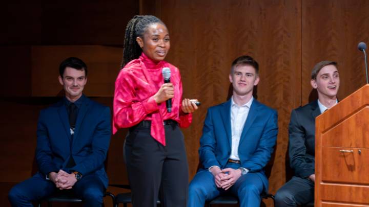 Senior Panashe Makuvaro presenting with her co-presenters seated behind her.