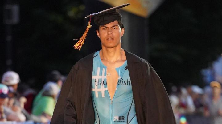 Calvin graduate Mitch Wong walking across the finish line