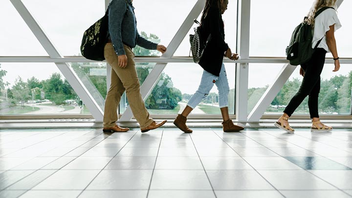 Three students walk across Calvin's Crossing.